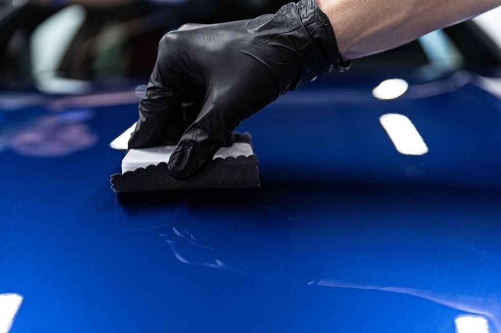 man-wearing-gloves-installing-self-healing-revivify-ceramic-coating-on-blue-car-Ontario-CA