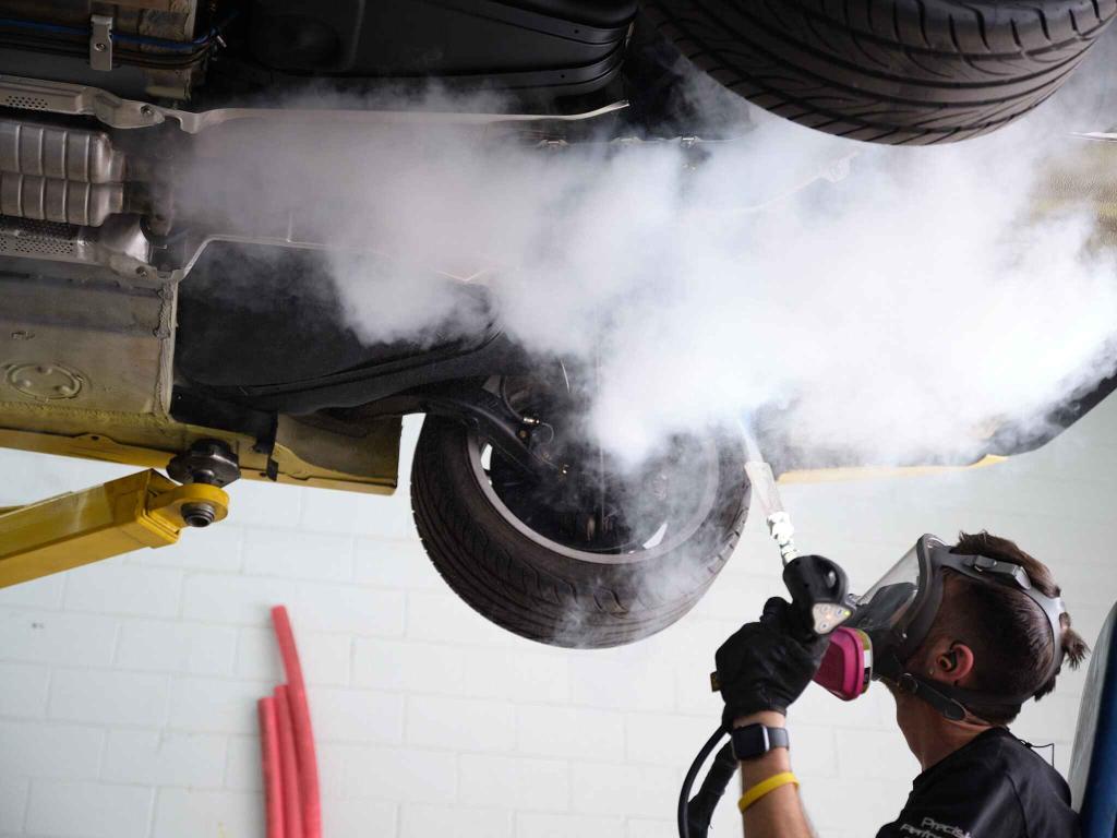 man-wearing-protective-equipment-performing-Dry Ice-Detailing-car-undercarriage-restoration-vehicle removing-rust-grime-oil-from-undercarriage-iPAC-Auto-Spa-Ontario-CA