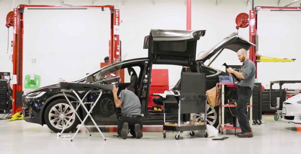 Two-men-working-in-garage-on-Tesla-Model-X-Doors-Windows-Suspension-Control-Arms-iPAC-Automotive-Ontario-CA