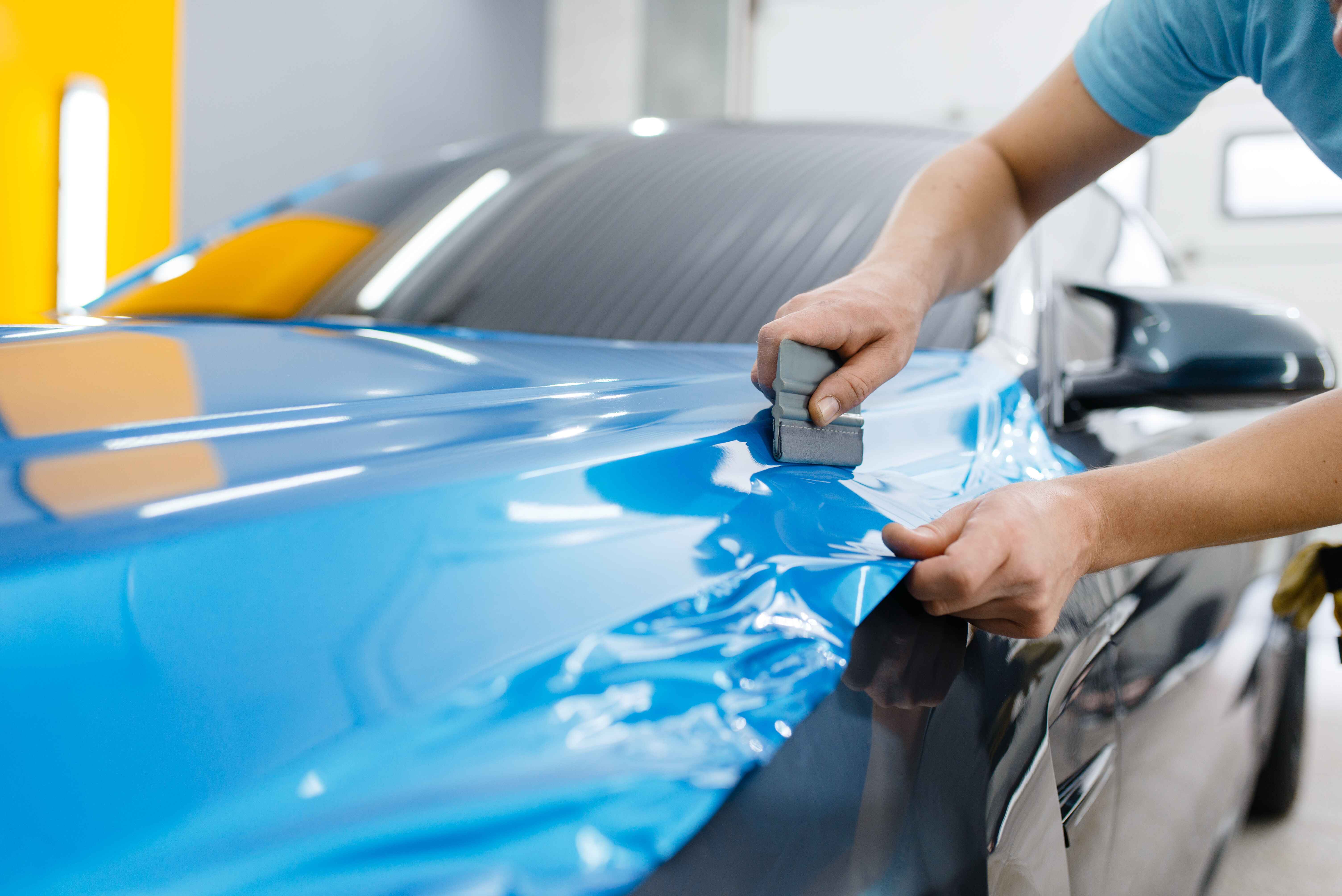 professional-male-installs-blue-protective-hydrophobic-vinyl-film-on-black-car-vinyl-color-change-iPAC-Auto-Spa-Ontario-CA