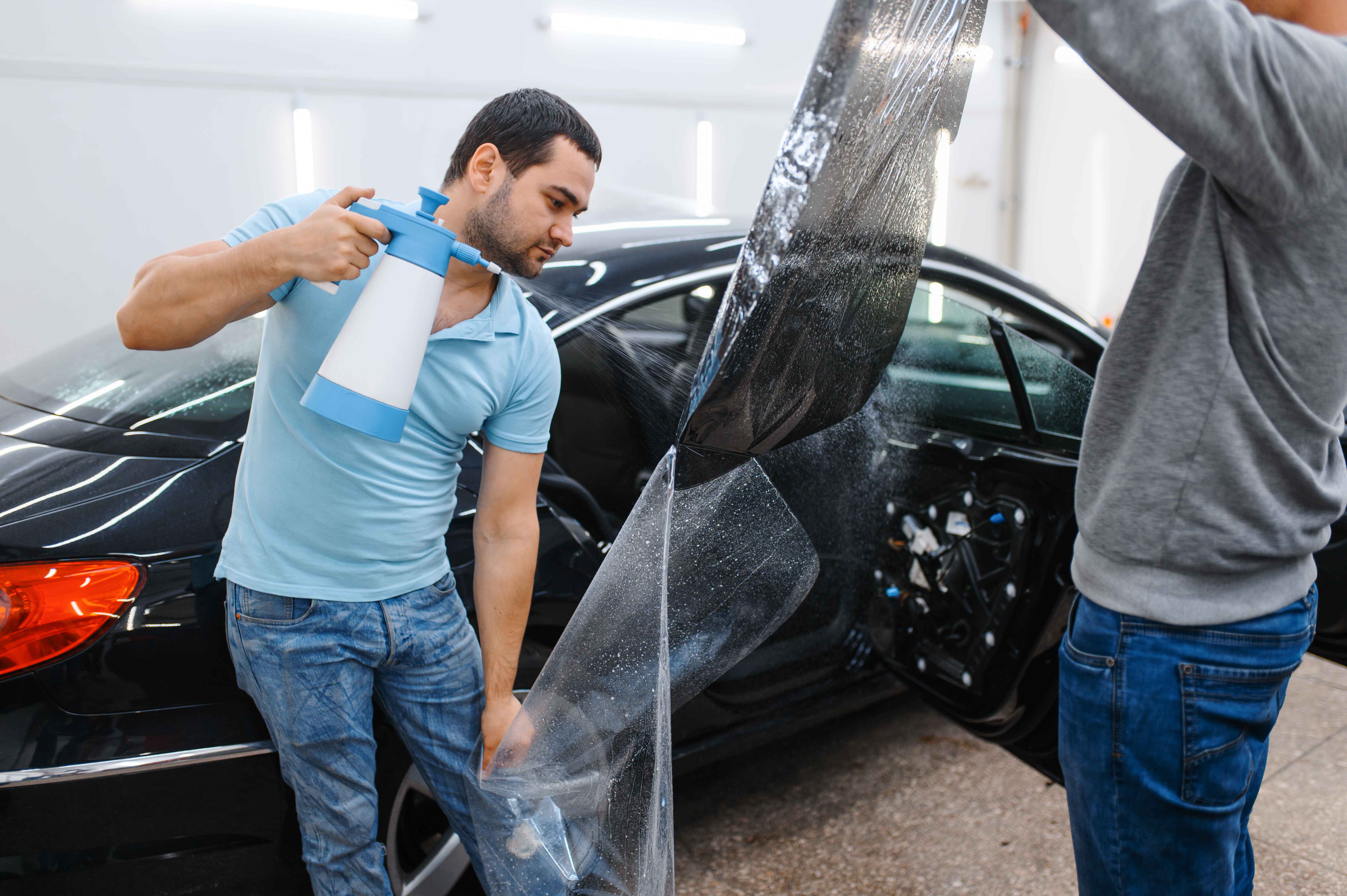 two-male-worker-with-spray-bottle-window-tinting-black-car-Ontario-CA